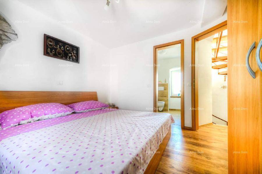 Schlafzimmer mit Doppelbett und Holzboden, mit direktem Zugang zu einem Badezimmer.