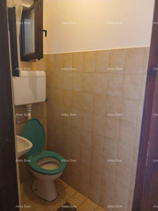 Separate Toilette mit WC, kleinem Waschbecken und halbhohen Fliesen an den Wänden.