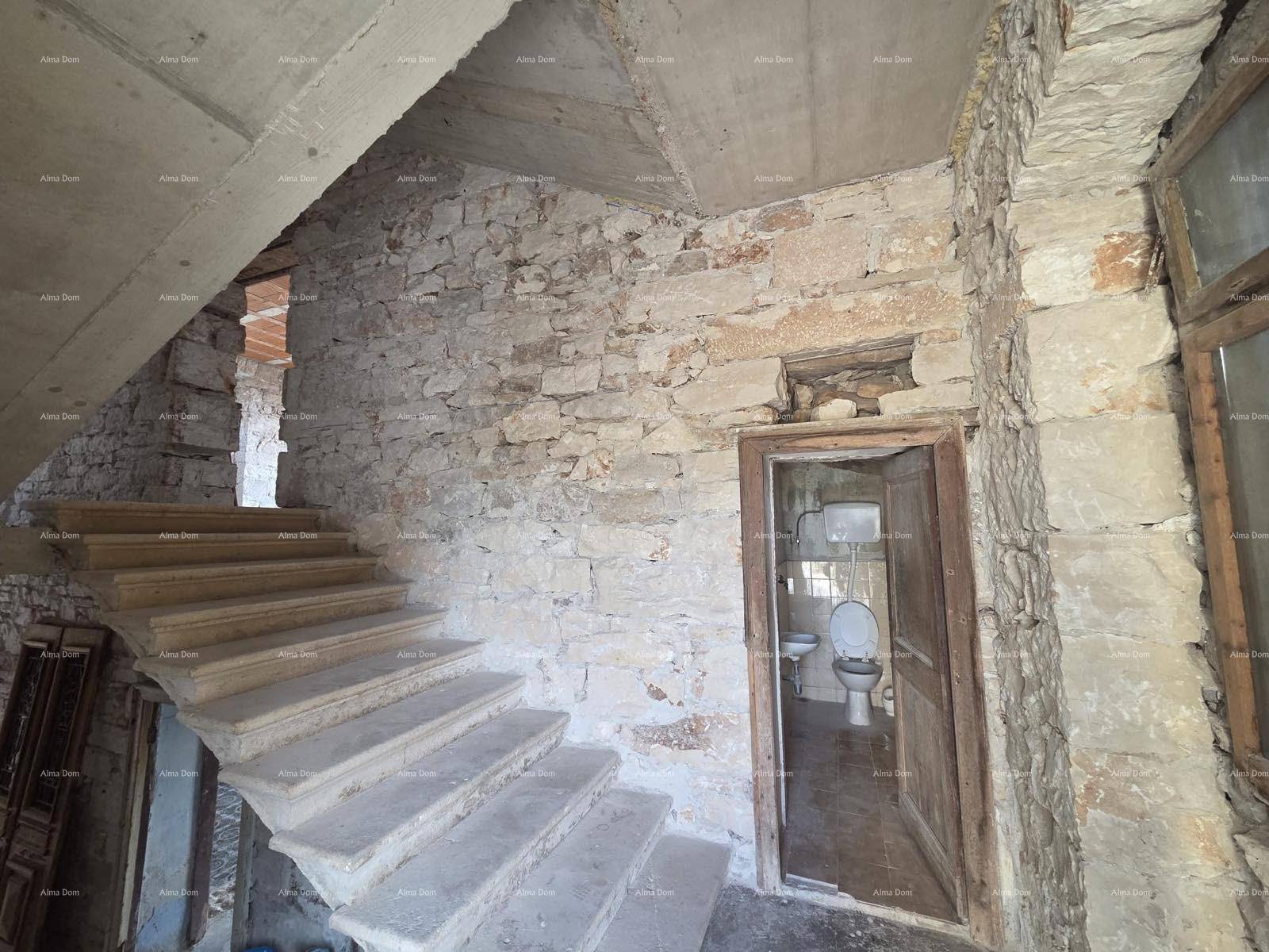 Treppenhaus mit Steinwänden und Blick auf eine kleine Toilette, die sich unter der Treppe befindet.