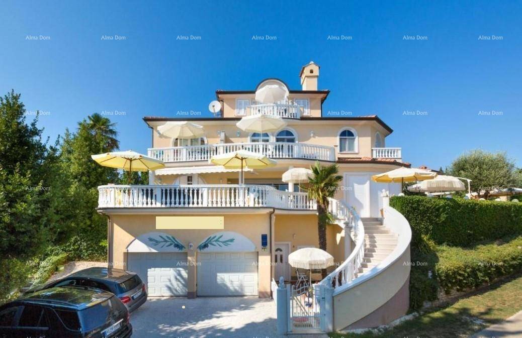 Die Villa von vorne mit mehreren Terrassen, Garagen und einer geschwungenen Außentreppe.