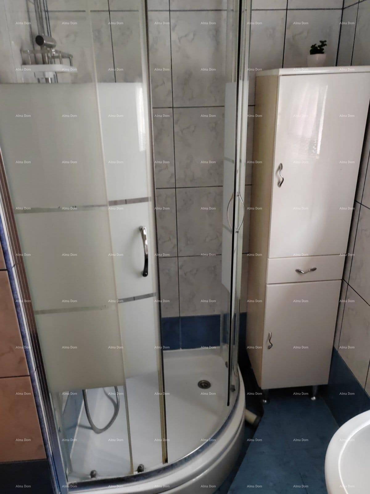 Badezimmer mit Duschkabine, Fliesen an Wänden und Boden sowie einem Hochschrank.