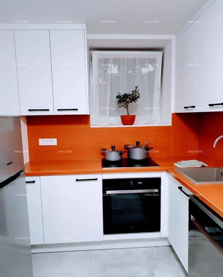 Moderne Küche mit weißen Schränken, orangefarbener Arbeitsplatte und integriertem Backofen, sehr gepflegt.
