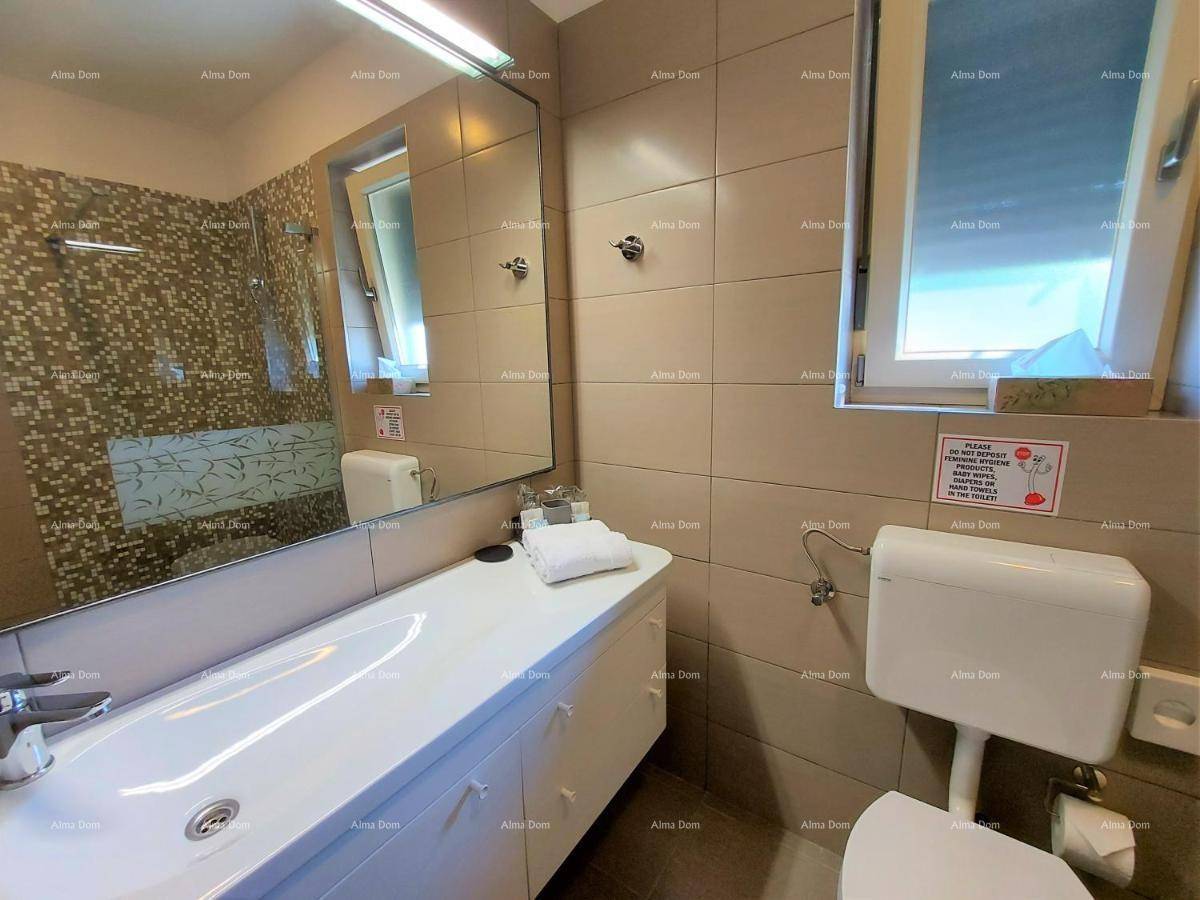 Funktionales Badezimmer mit Waschtisch, Spiegel und Toilette, ausgestattet mit hellen Fliesen.