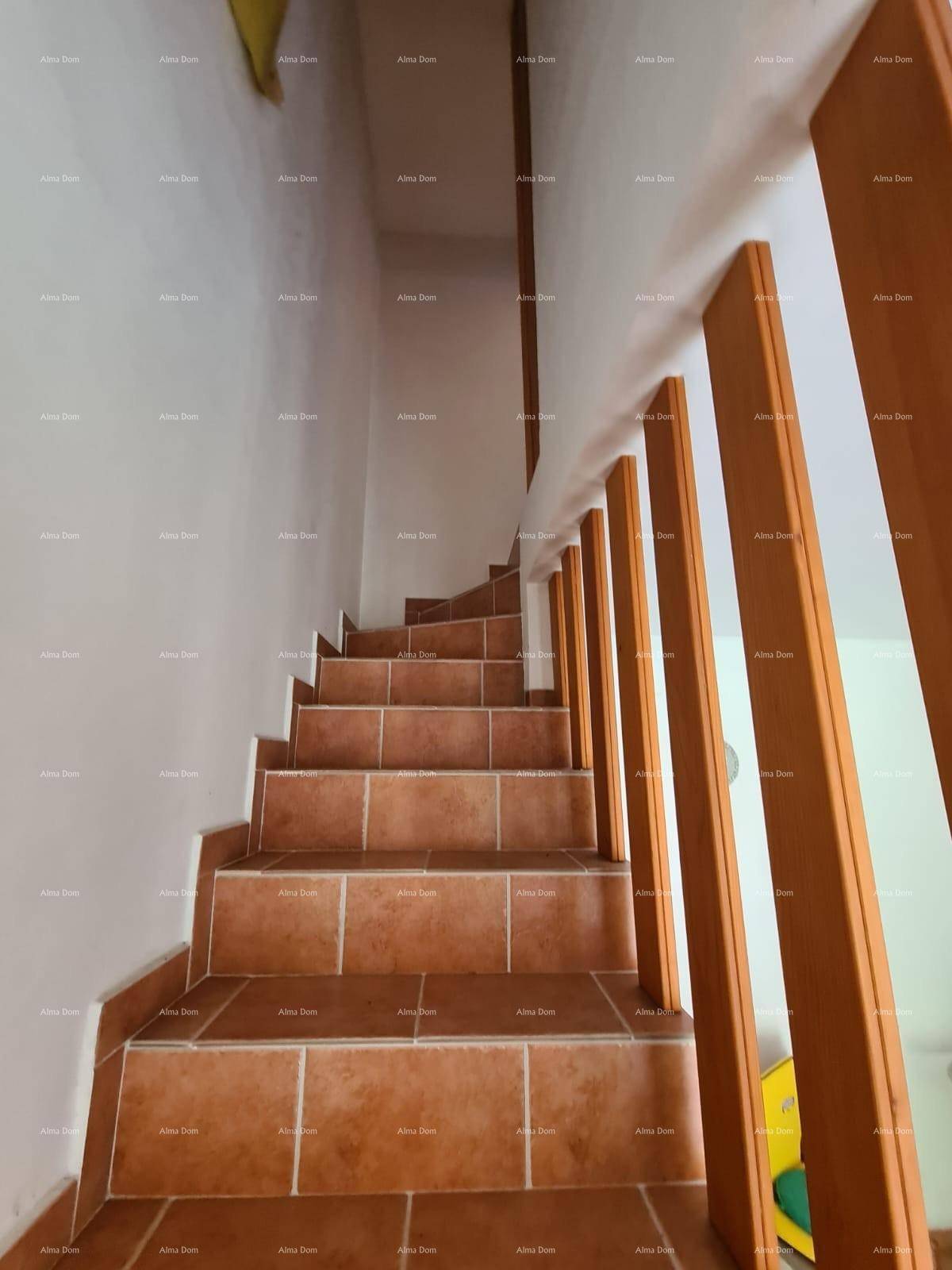 Detailansicht der gefliesten Treppe mit Holzgeländer, die in die obere Etage führt.