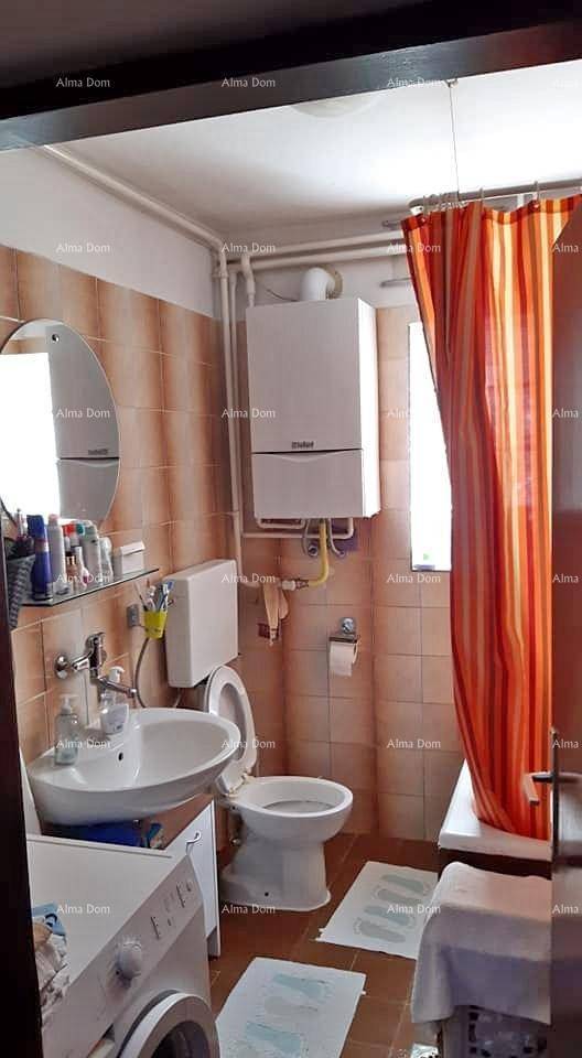 Gefliestes Badezimmer mit Toilette, Waschbecken, Waschmaschine und Duschbereich mit farbiger Duschvorhang.