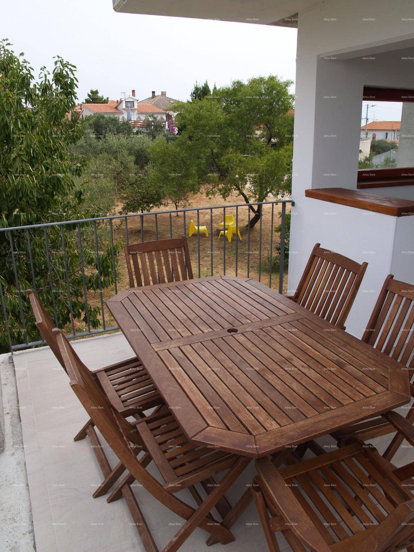 Balkon mit Holztisch und Stühlen, bietet einen Blick auf die grüne Umgebung.