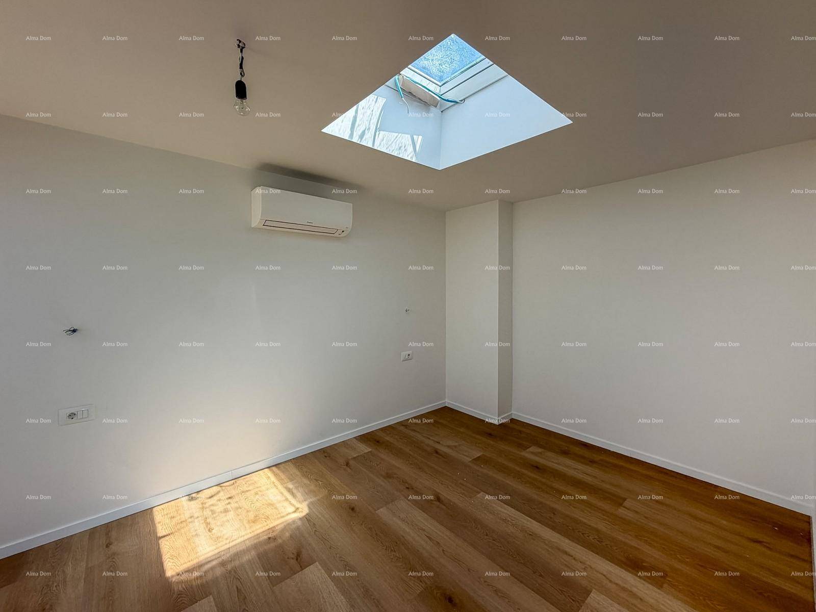Lichtdurchflutetes Zimmer mit Holzboden, großem Dachfenster und Klimaanlage.