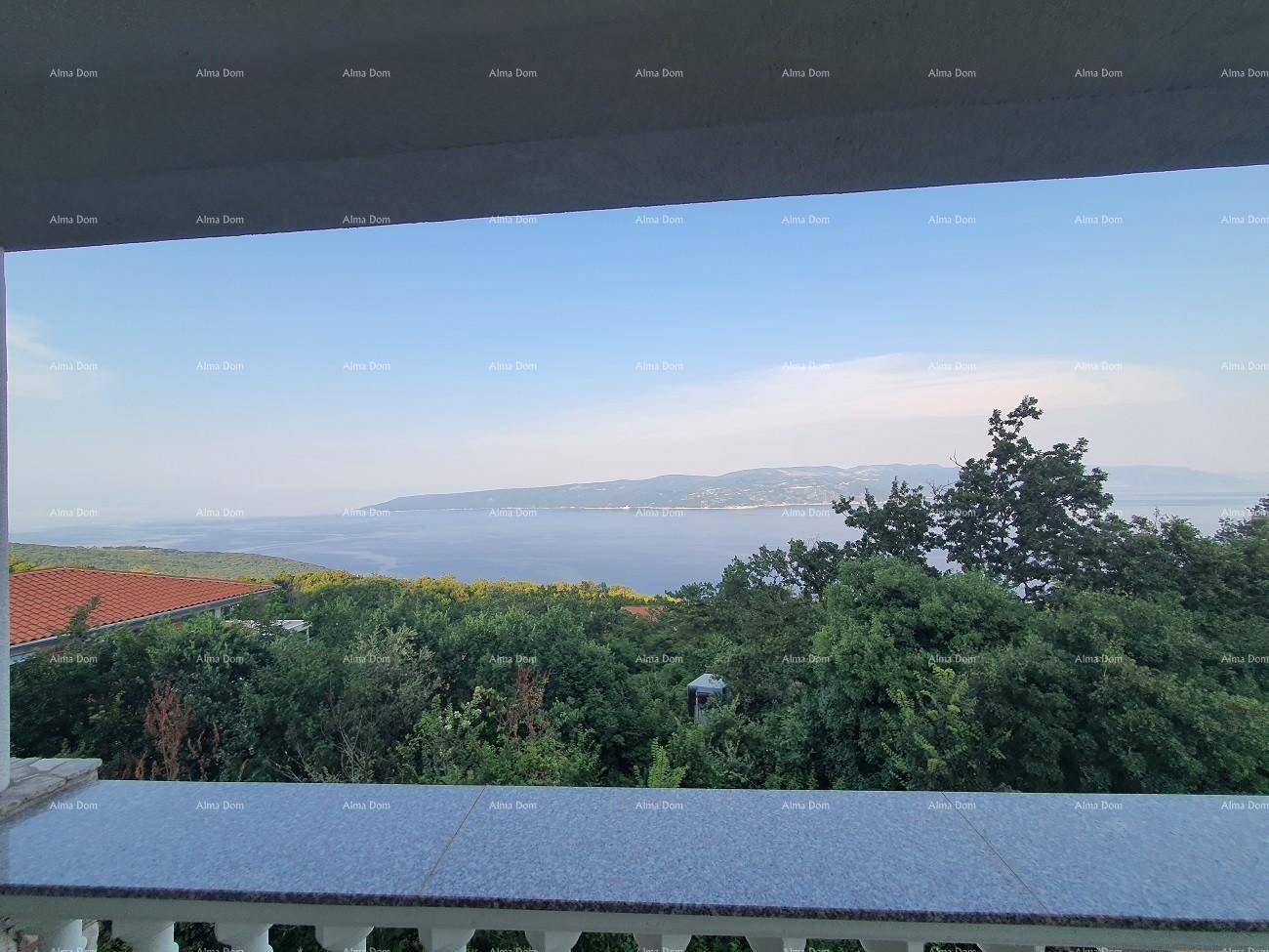 Weitläufiger Meerblick von einem Balkon, umgeben von grünen Bäumen und der Küstenlandschaft.
