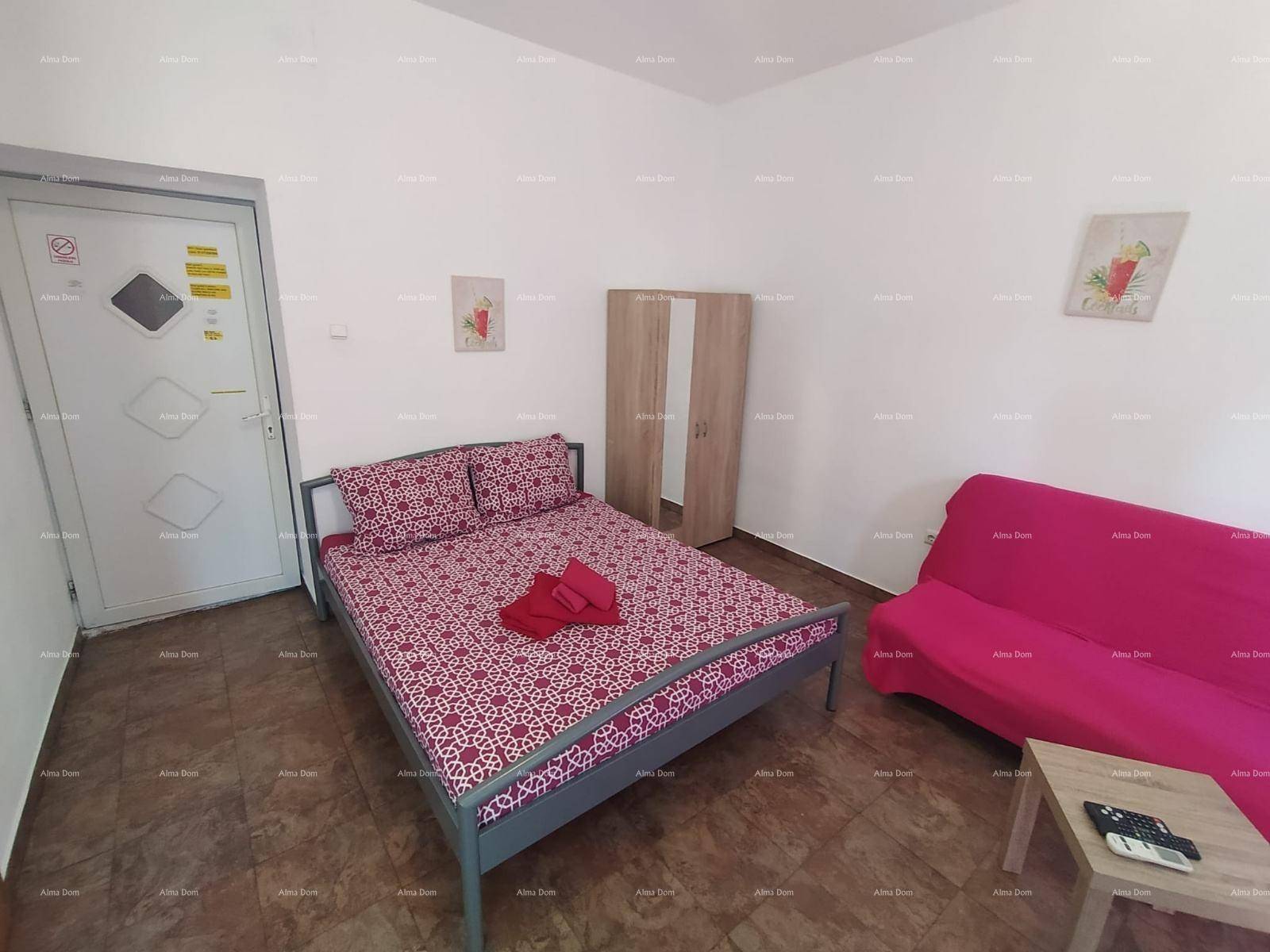 Schlafbereich in einem Studio-Apartment mit Doppelbett, Sofa und Kleiderschrank, funktional eingerichtet.