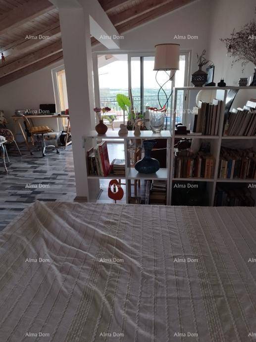 Helles Schlafzimmer im Dachgeschoss mit schrägen Decken, großem Fenster und Zugang zu einem Balkon.