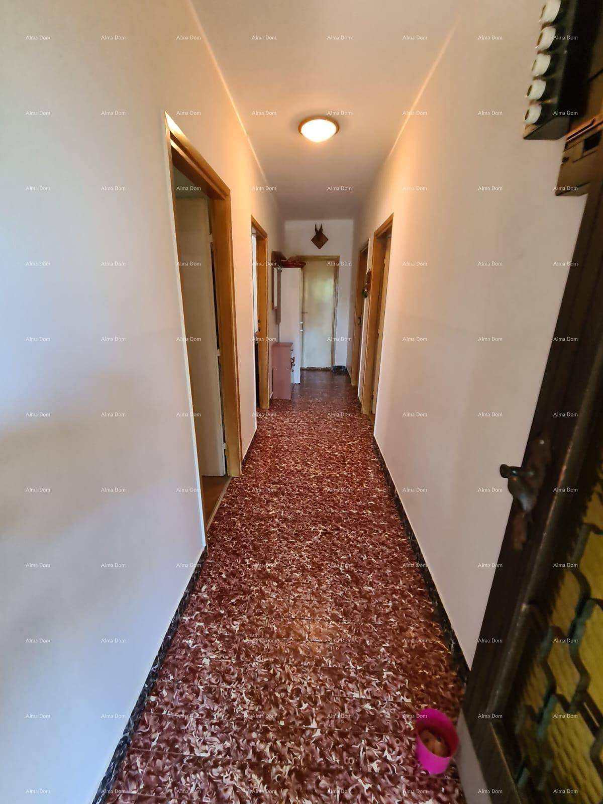 Langer Flur mit gemustertem Boden und mehreren Türen zu den Zimmern.