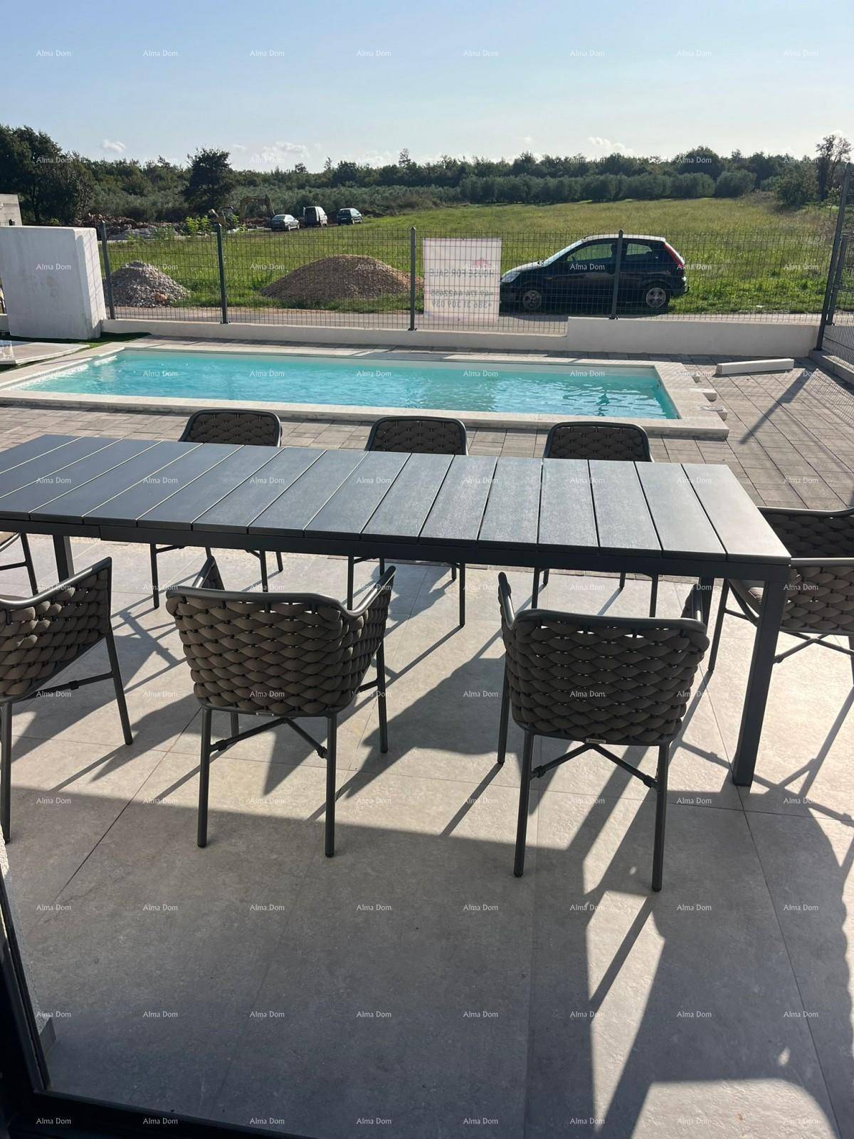Sonniger Außenbereich mit Esstisch, Stühlen und Pool, umgeben von einer ländlichen Landschaft.
