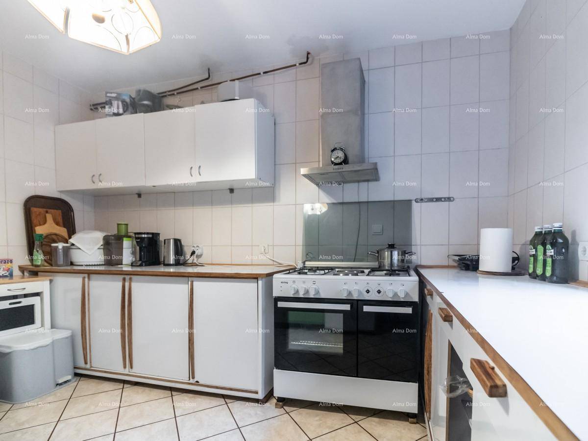 Funktionale Küche mit weißen Schränken, Gasherd, Backofen und Dunstabzugshaube.