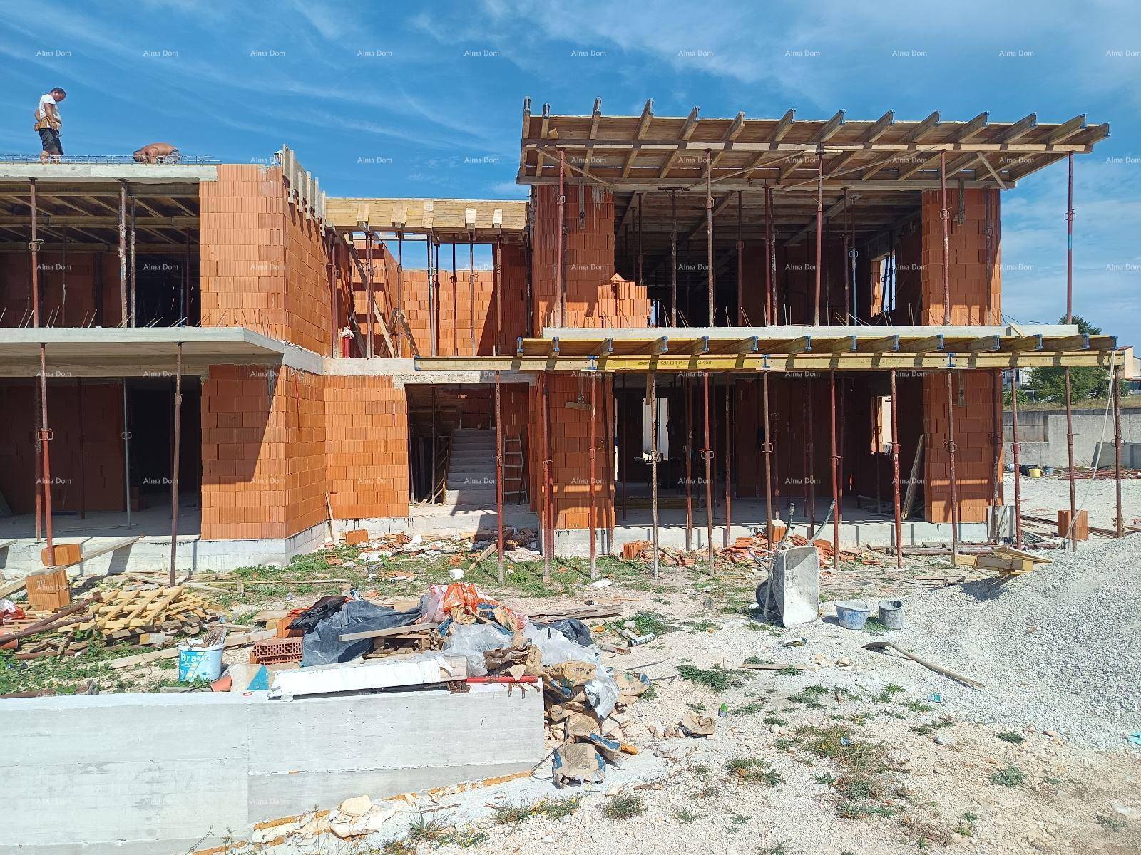 Rohbau eines Mehrfamilienhauses mit Gerüsten und Baumaterialien auf dem Gelände.