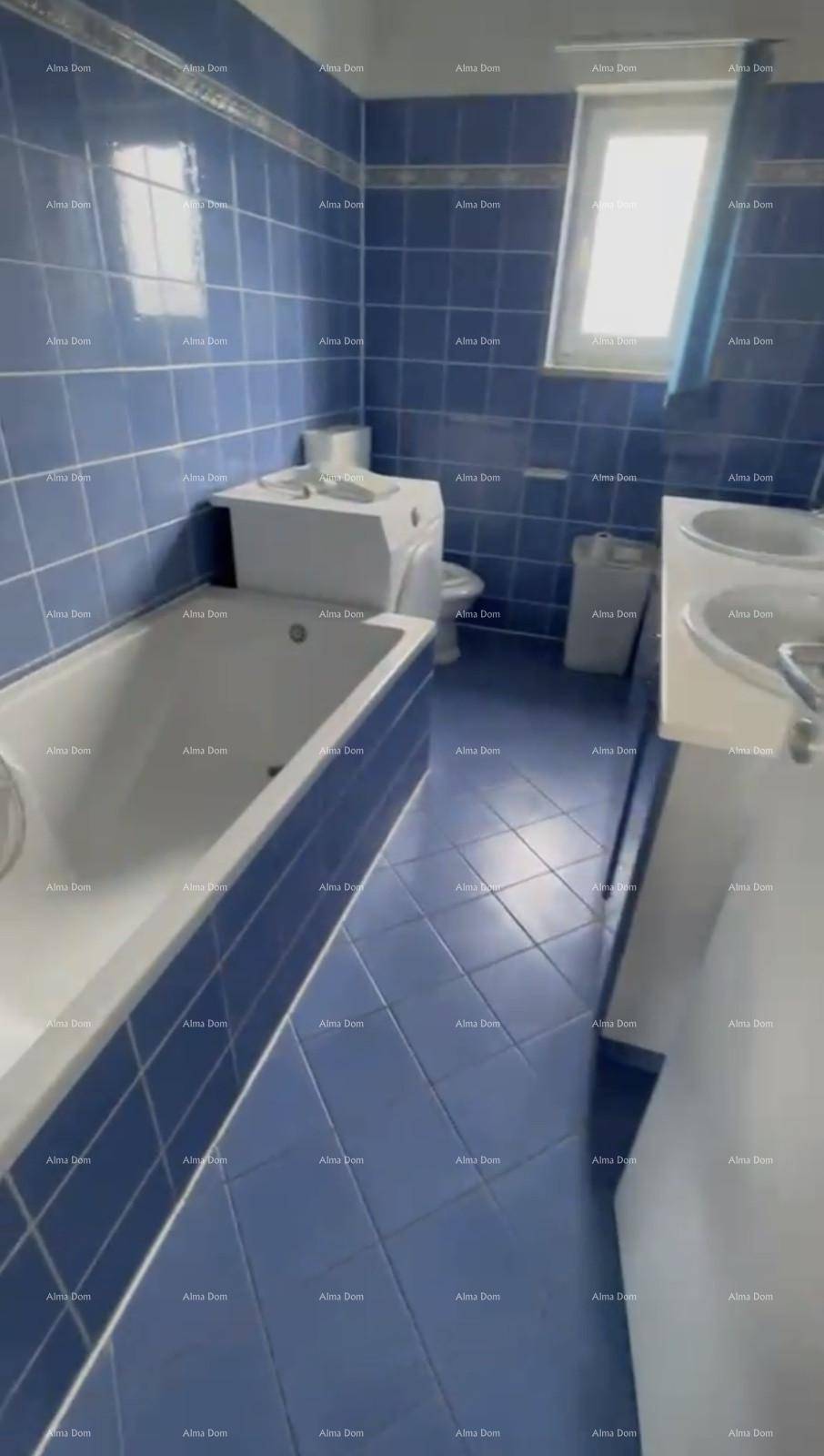 Badezimmer mit blauen Fliesen, Badewanne, Toilette und Waschbecken, gut beleuchtet.