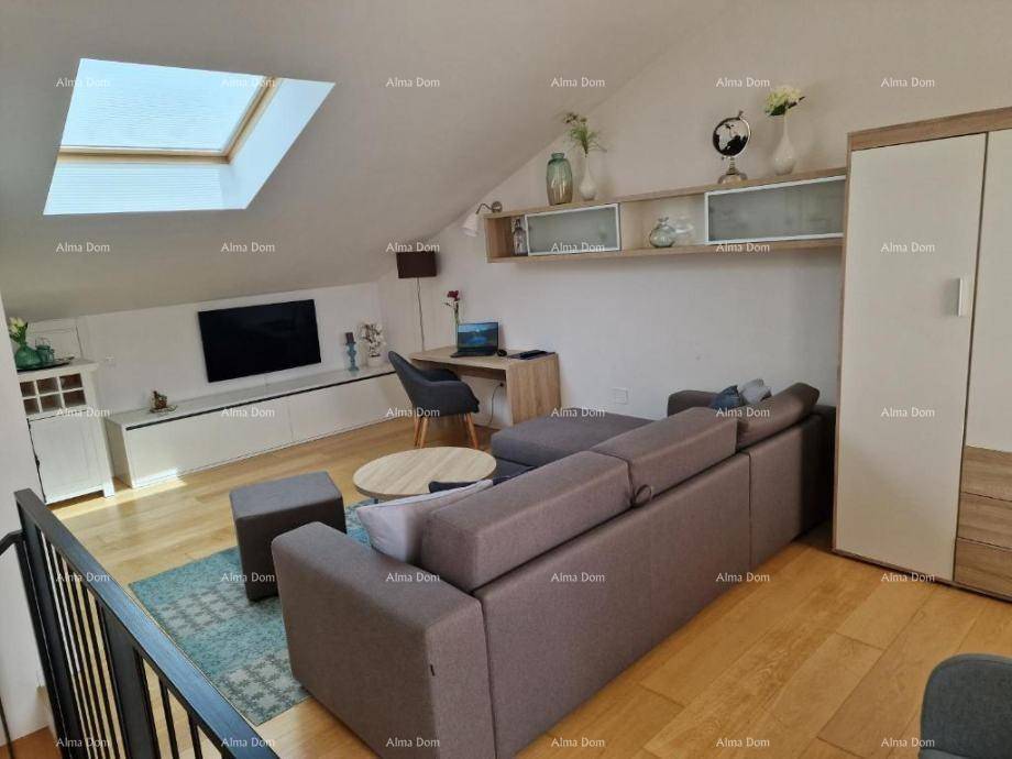 Helles Wohnzimmer im Dachgeschoss mit Sofa, Schreibtisch und Dachfenster.