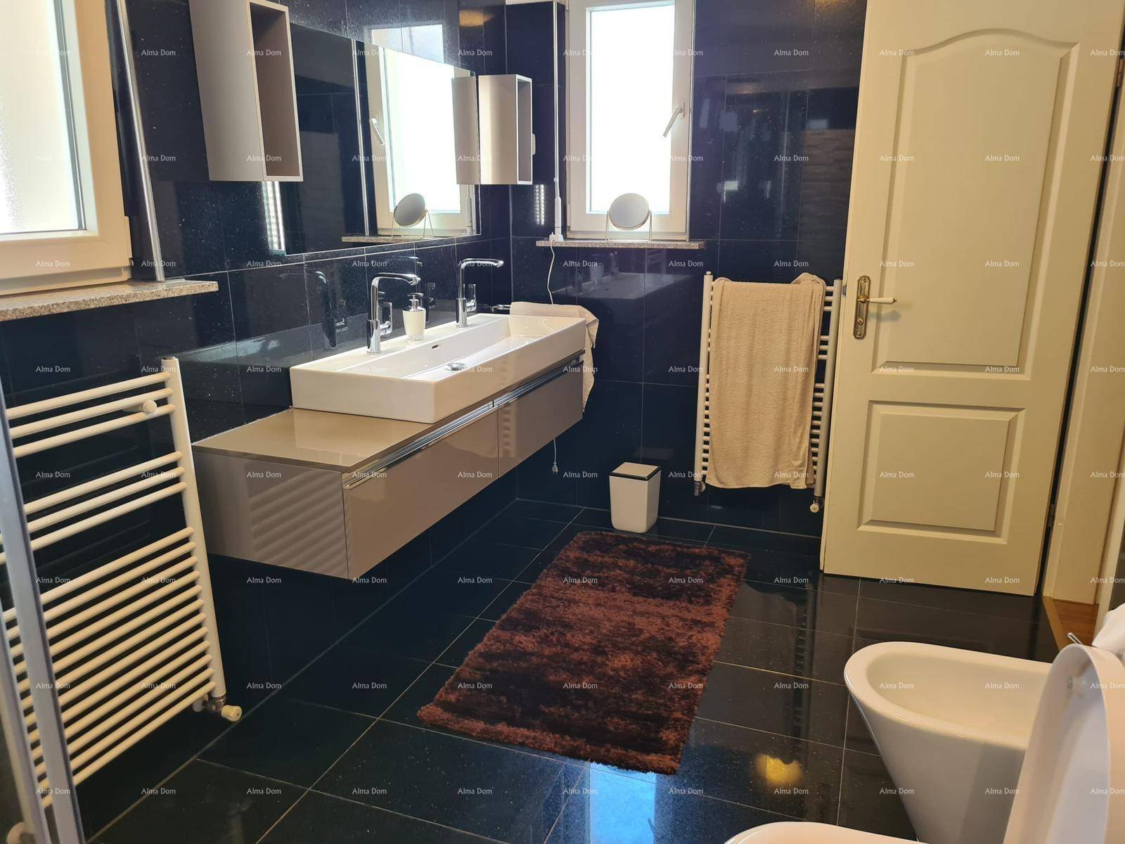 Modernes Badezimmer mit dunklen Fliesen, Doppelwaschbecken und beheiztem Handtuchhalter.