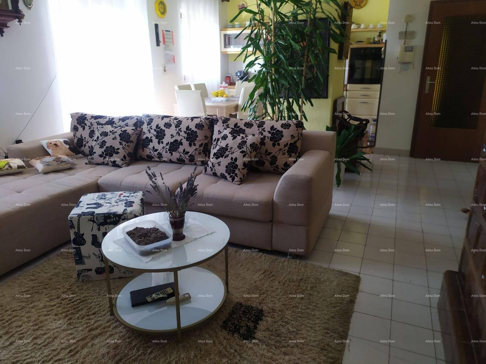 Heller Wohnbereich mit großem Ecksofa, Couchtisch und Essbereich im Hintergrund, mit Fliesenboden.