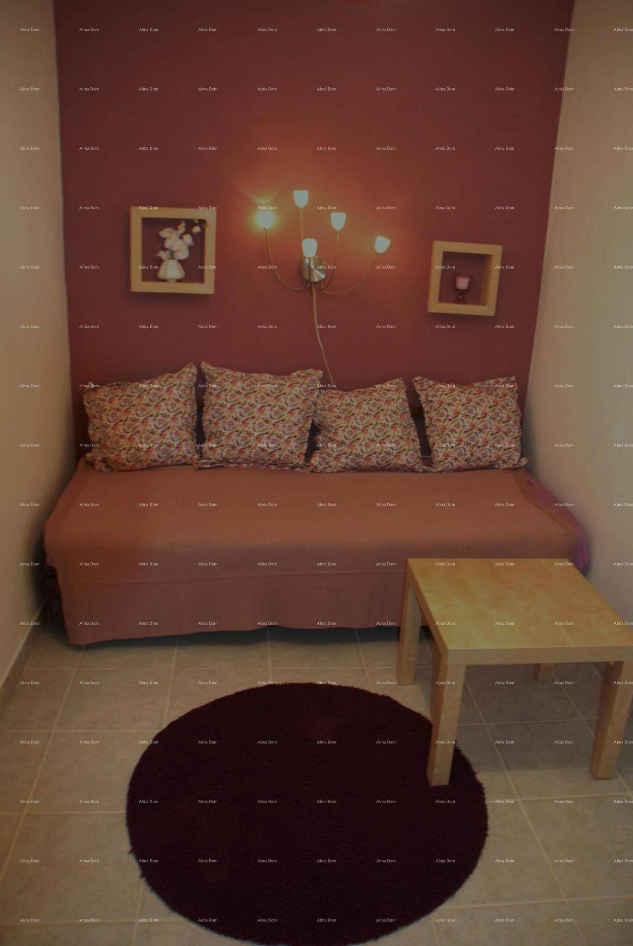 Kleiner Raum mit rotem Sofa, Holztisch und rundem Teppich.