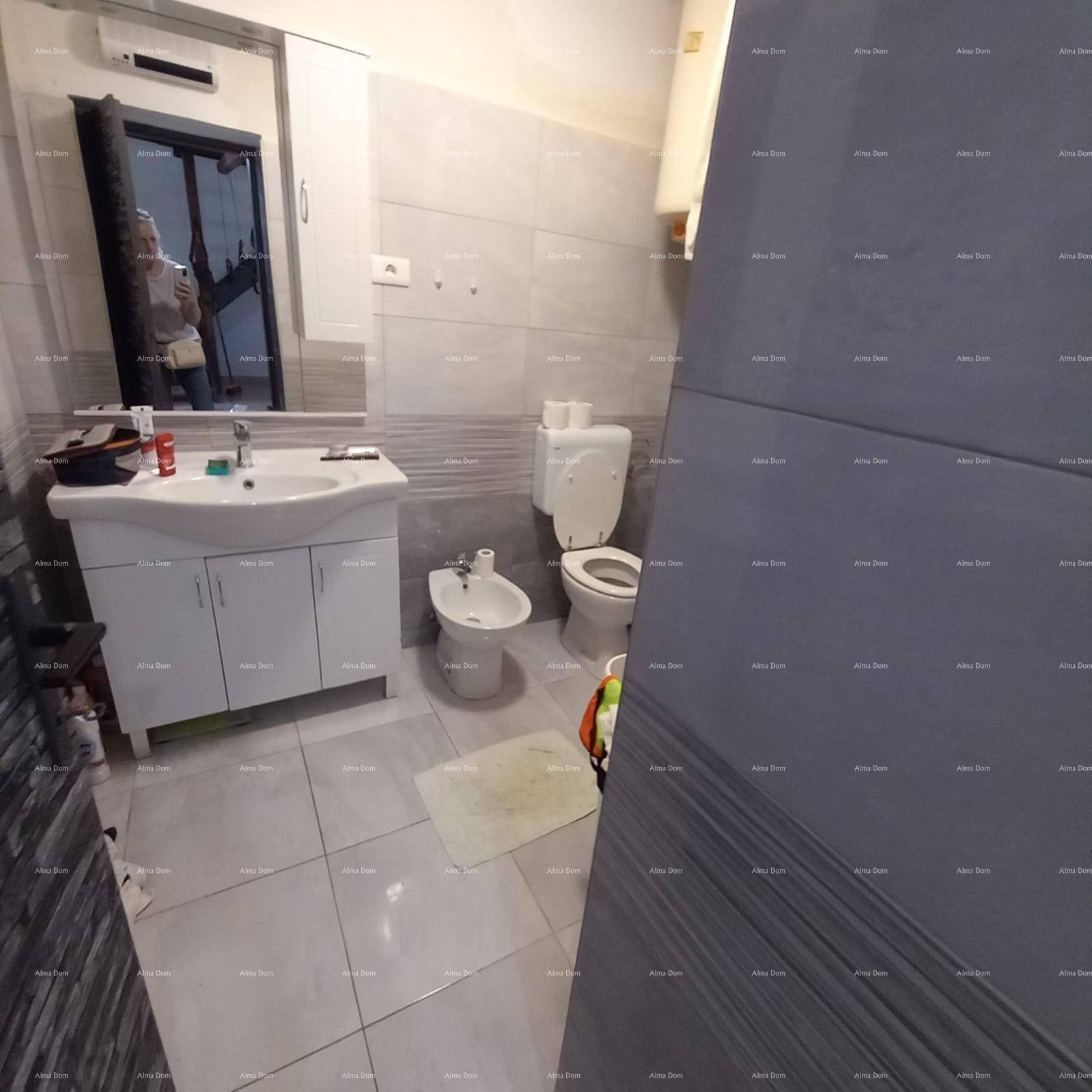 Modernes Badezimmer mit grauen Fliesen, Waschbecken, Toilette, Bidet und Duschbereich.