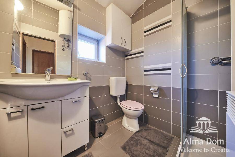Modernes Badezimmer mit Dusche, WC und Waschbecken in neutralen Grautönen.