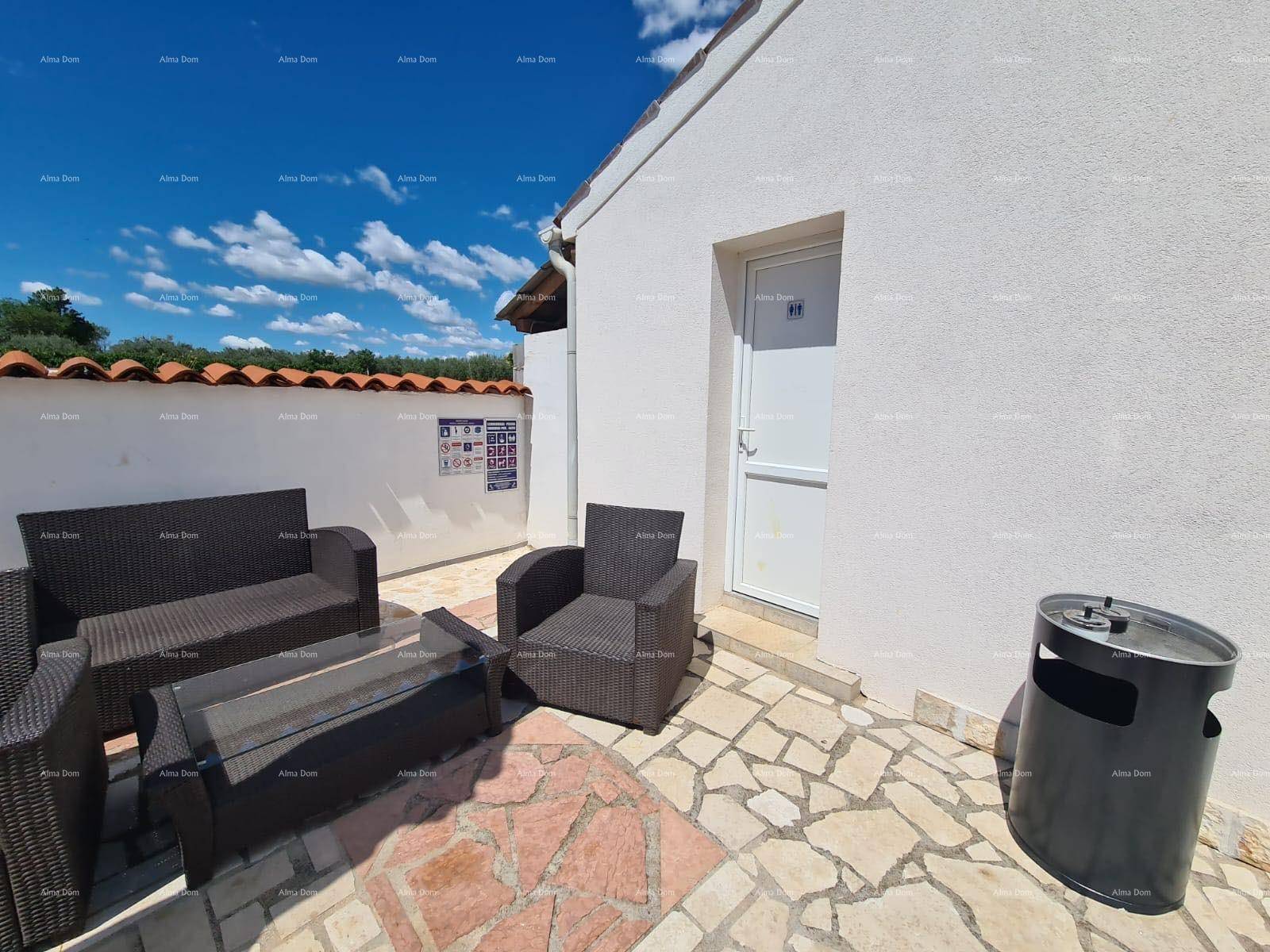 Gemütliche gepflasterte Terrasse mit Korbmöbeln und einem Eingang zu einem Nebengebäude.
