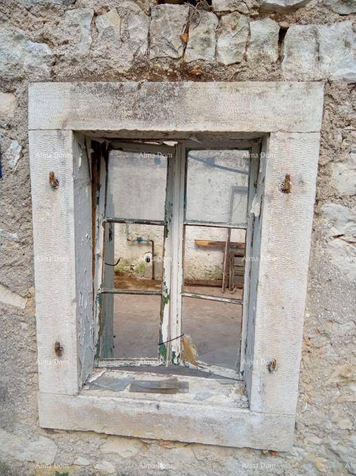 Altes Fenster mit zerbrochenem Rahmen und Blick in den verfallenen Innenraum eines Steinhauses.