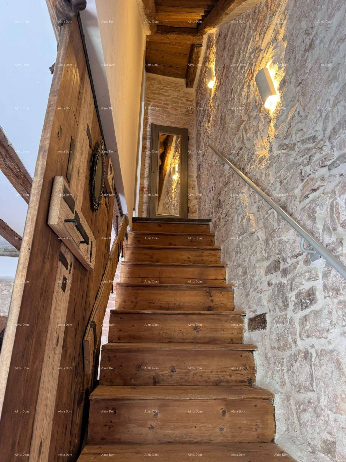 Holztreppe mit Steinwänden und indirekter Beleuchtung, die zu den oberen Etagen führt.