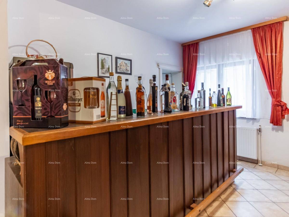 Barbereich mit Holztheke, verschiedenen Flaschen und einem Fenster mit roten Vorhängen.