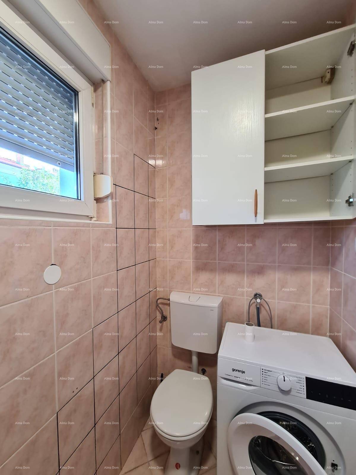 Badezimmer mit WC, Waschmaschine, Fenster und beigefarbenen Fliesen.
