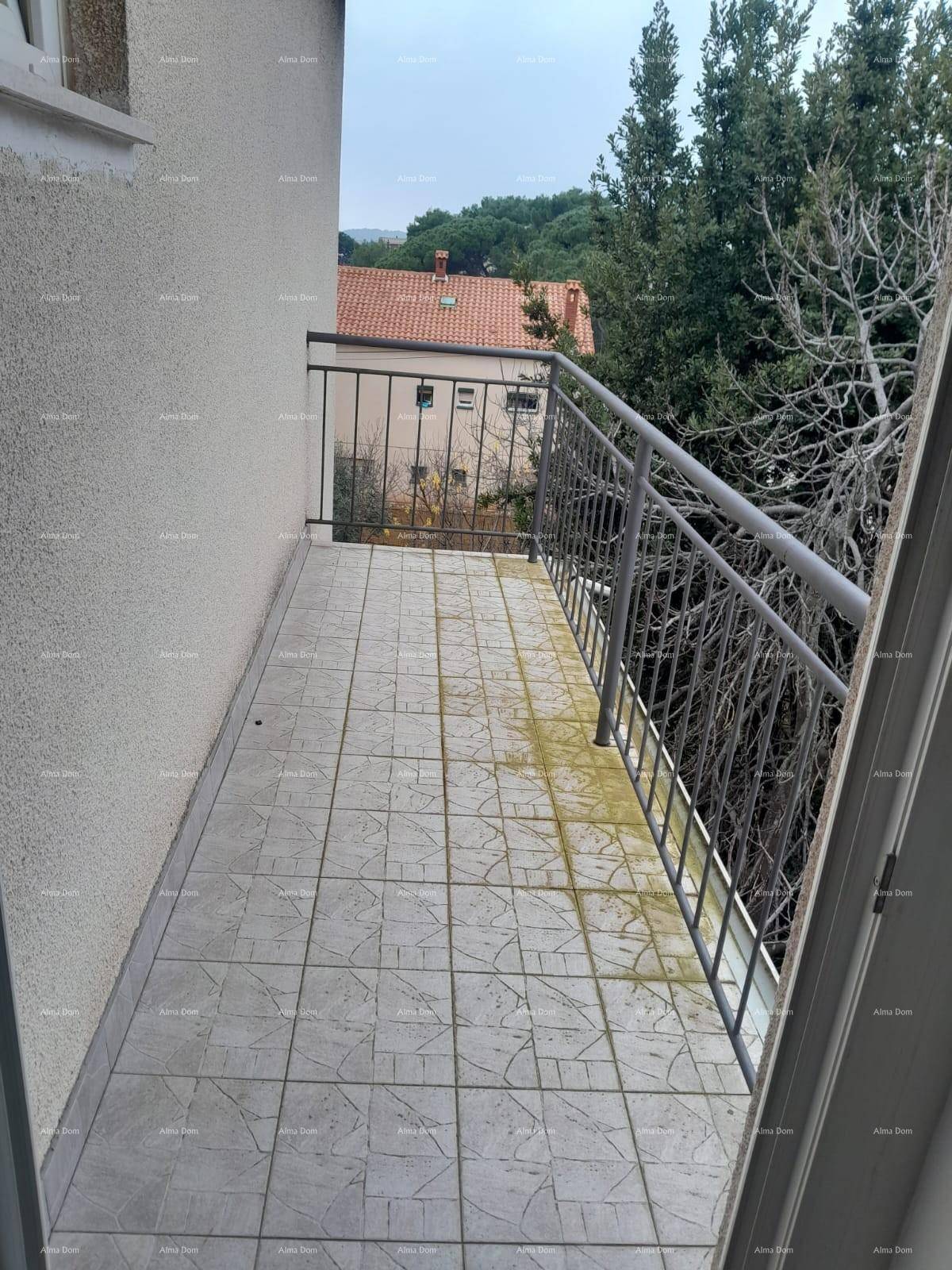 Kleiner Balkon mit Fliesenboden und Metallgeländer, umgeben von Bäumen und Blick auf ein Gebäude.
