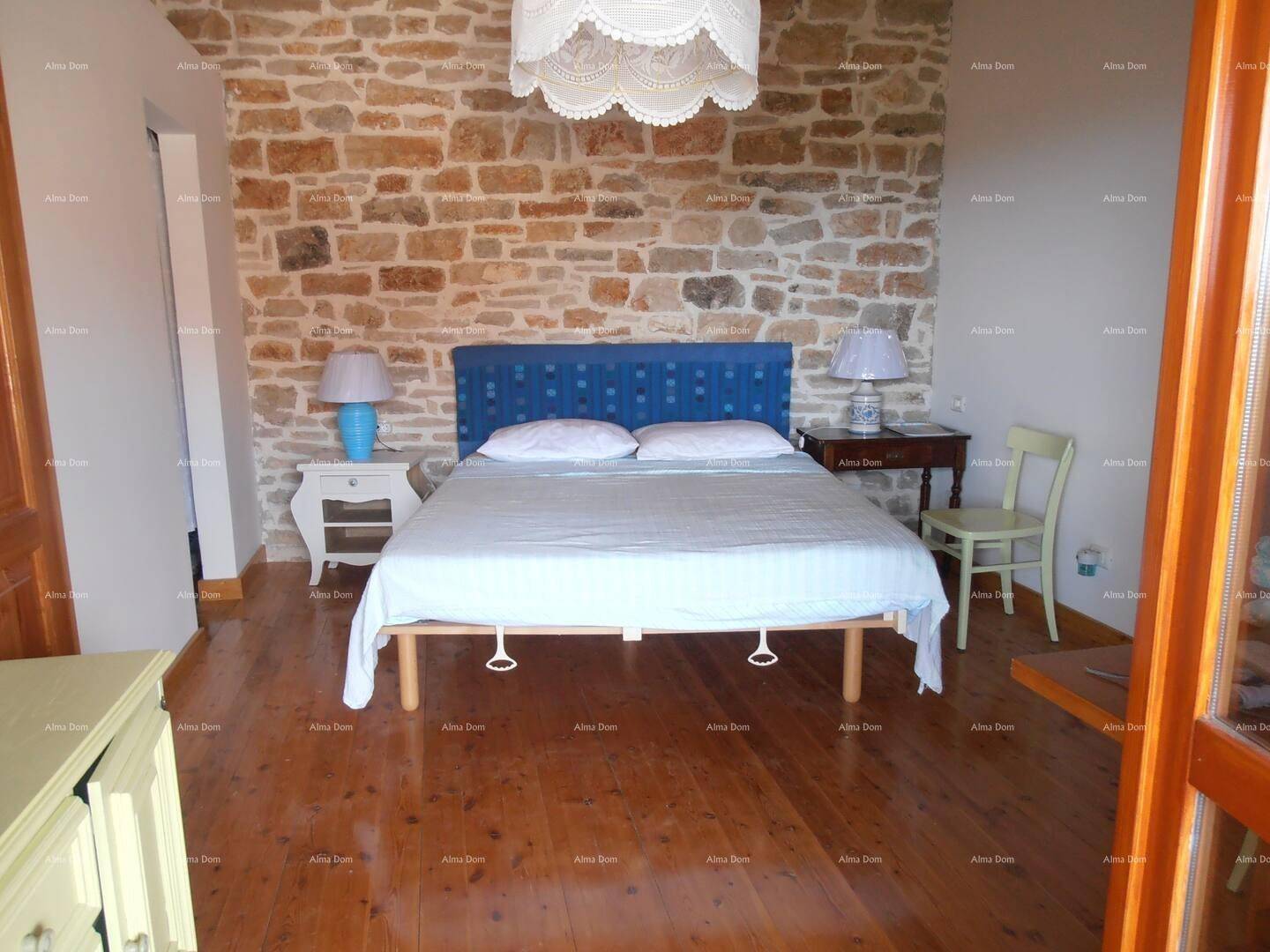 Geräumiges Schlafzimmer mit Holzboden, freiliegender Steinwand und einem großen Doppelbett.
