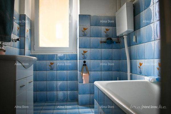 Badezimmer mit blauen Fliesen, Badewanne, Waschbecken und einem Fenster für Tageslicht.
