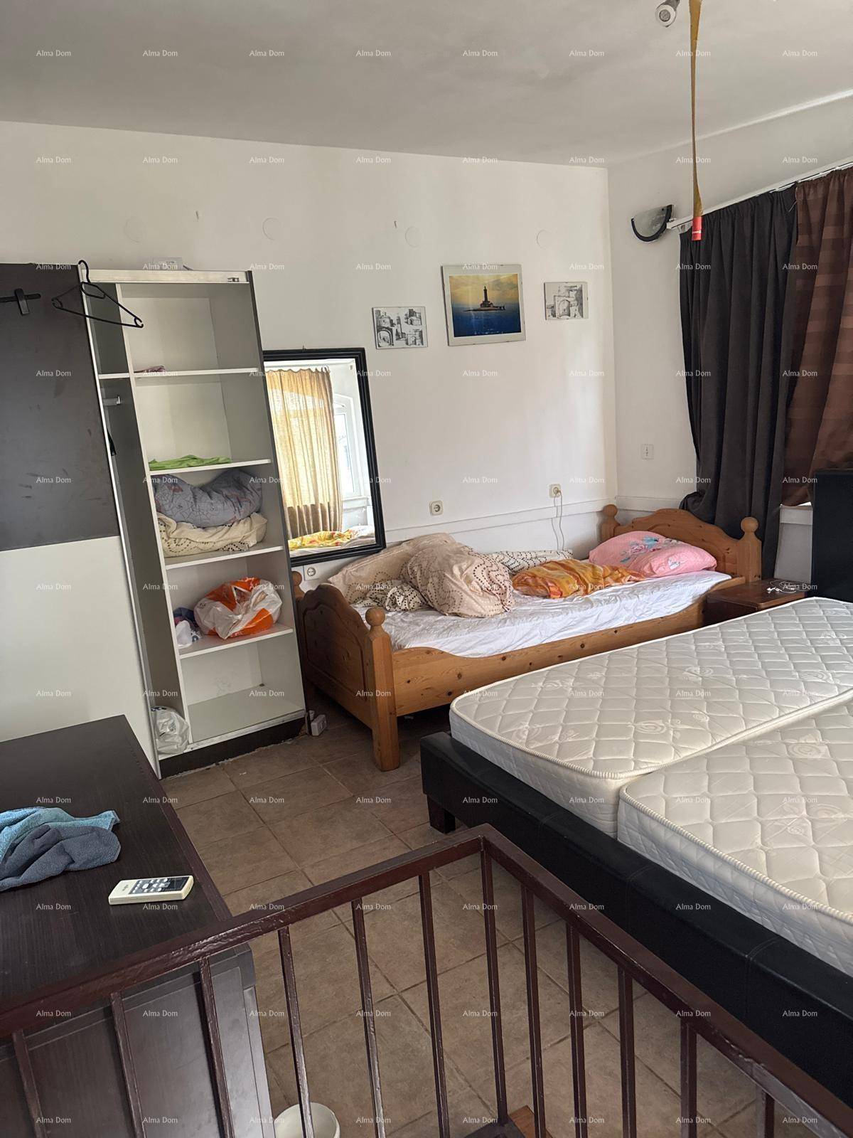 Schlafzimmer mit mehreren Betten, offenem Kleiderschrank und einem Spiegel, auf einer oberen Etage gelegen.