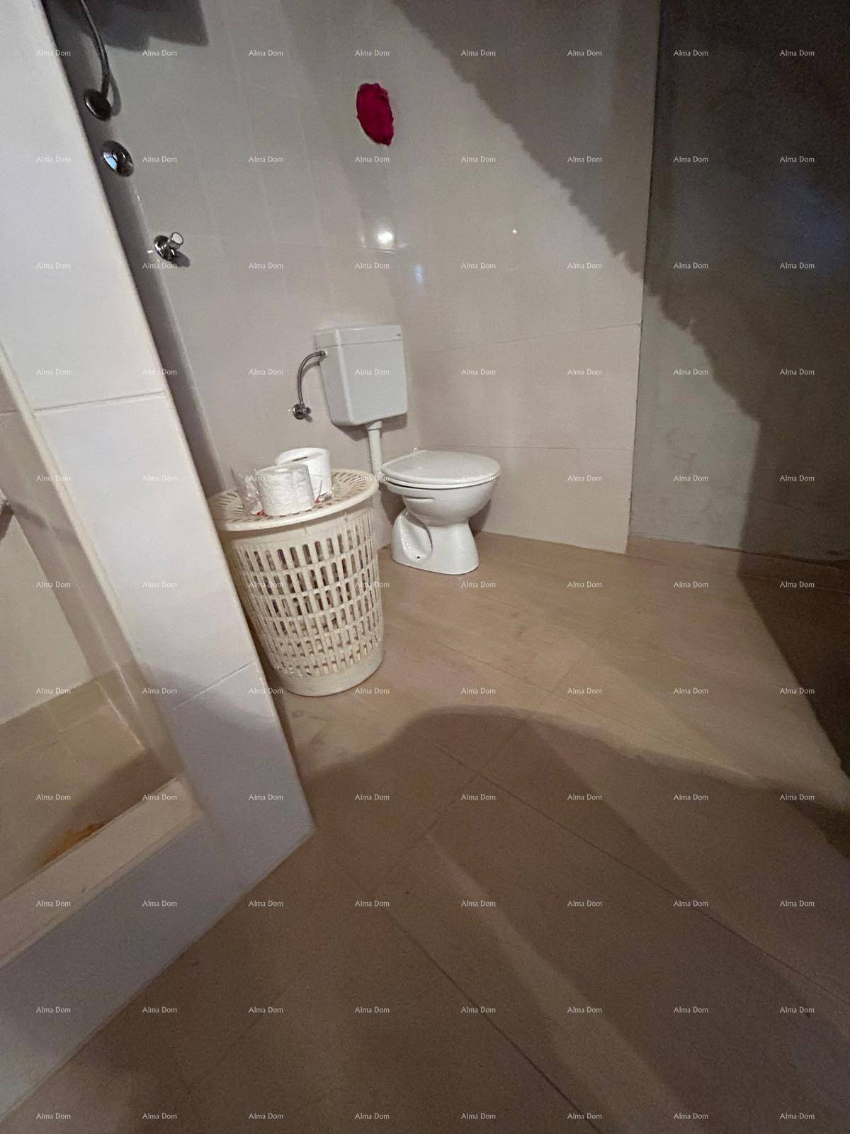 Badezimmer mit Toilette und Duschbereich, ausgestattet mit hellen Wand- und Bodenfliesen.