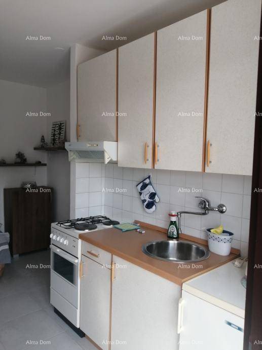 Funktionale Küchenzeile mit weißen Oberschränken, Gasherd und einfacher Ausstattung.
