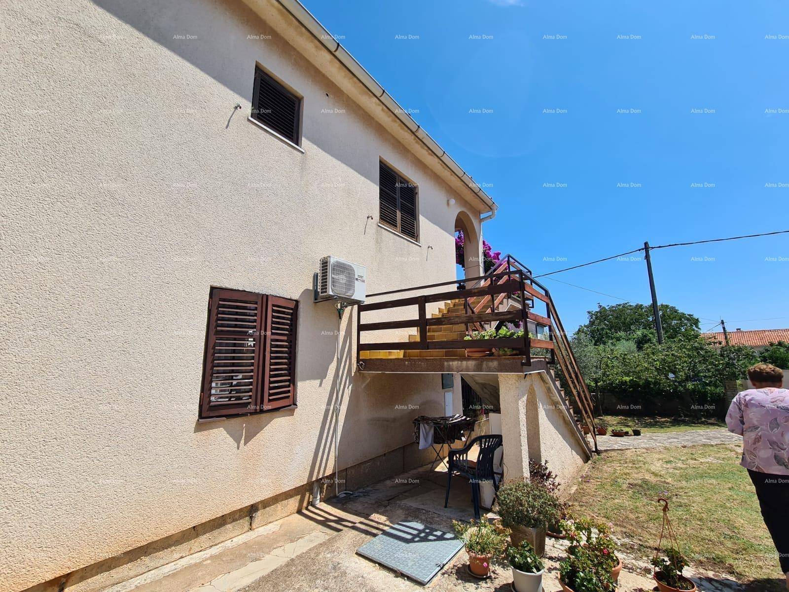 Seitenansicht des Hauses mit Außentreppe, Balkon und blühenden Pflanzen.