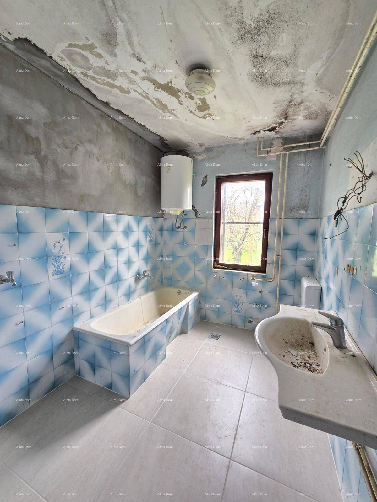 Badezimmer mit blauen Fliesen, Badewanne und Waschbecken, das eine umfassende Renovierung benötigt und ein Fenster hat.