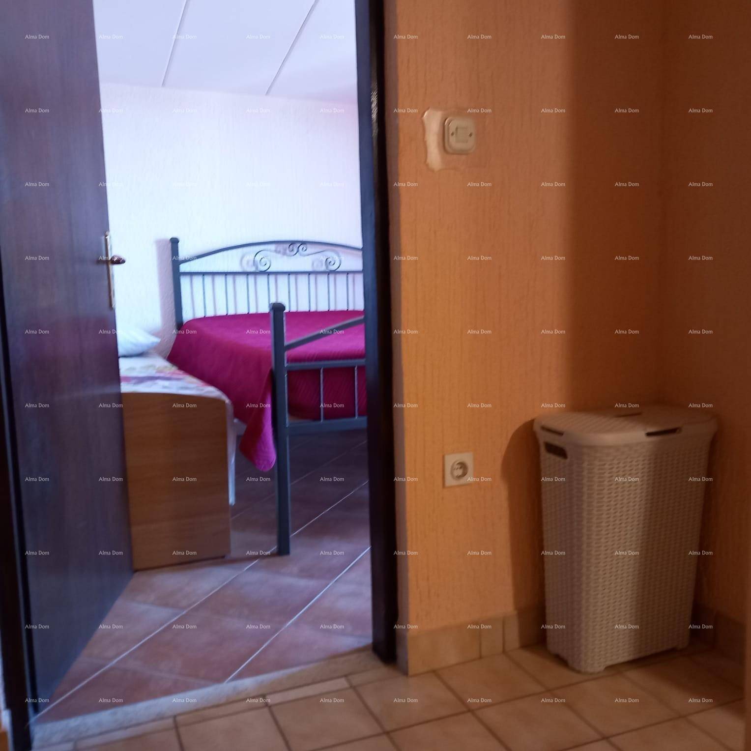 Flur mit Blick in ein Schlafzimmer mit Fliesenboden und einfacher Einrichtung.