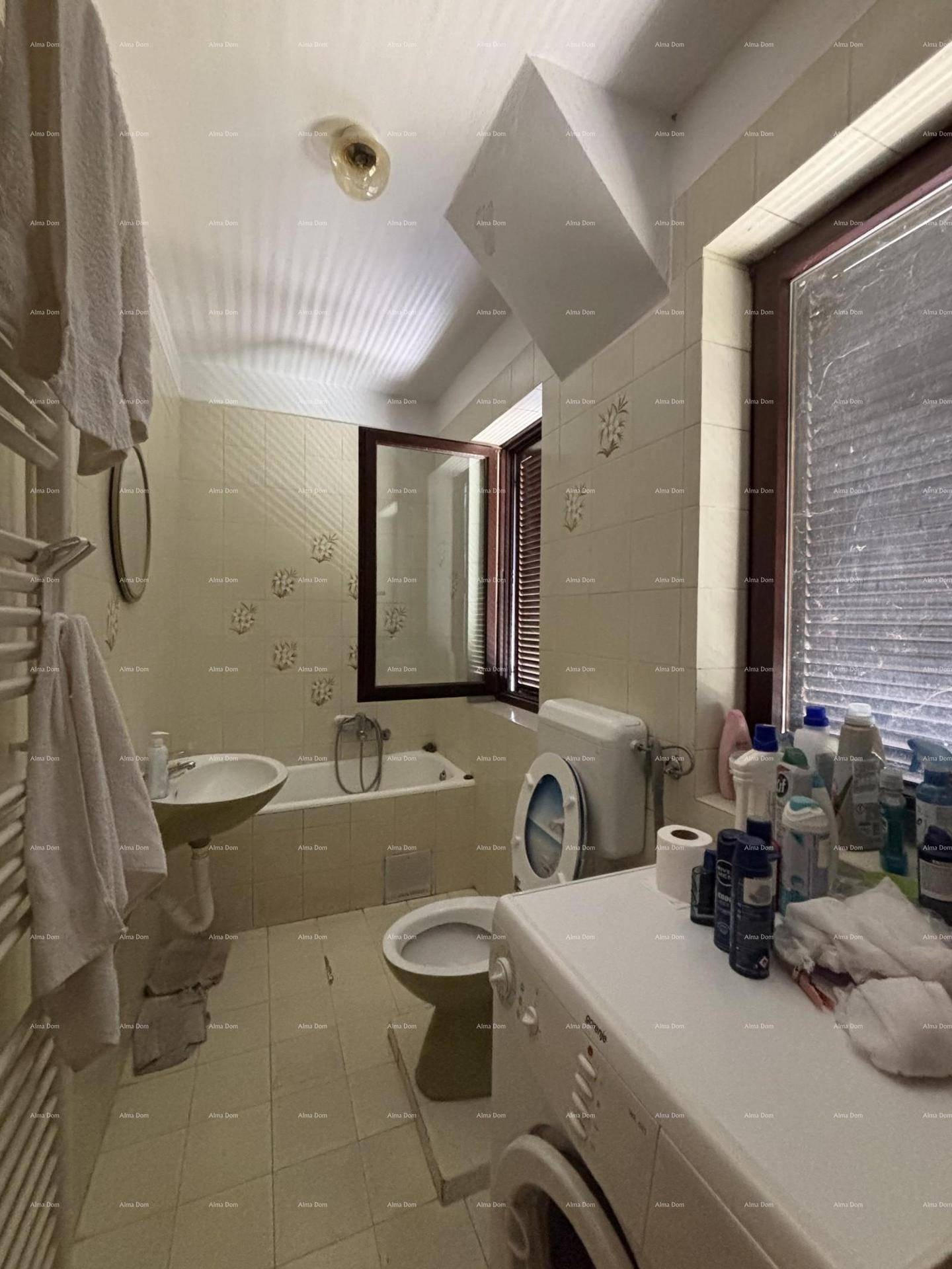 Badezimmer mit Badewanne, WC, Waschbecken und Waschmaschine, hell gefliest.