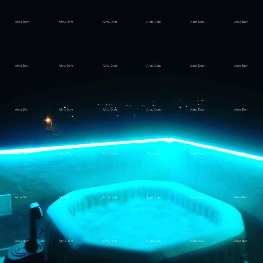 Whirlpool auf der Terrasse bei Nacht, beleuchtet mit blauem Licht unter klarem Himmel.