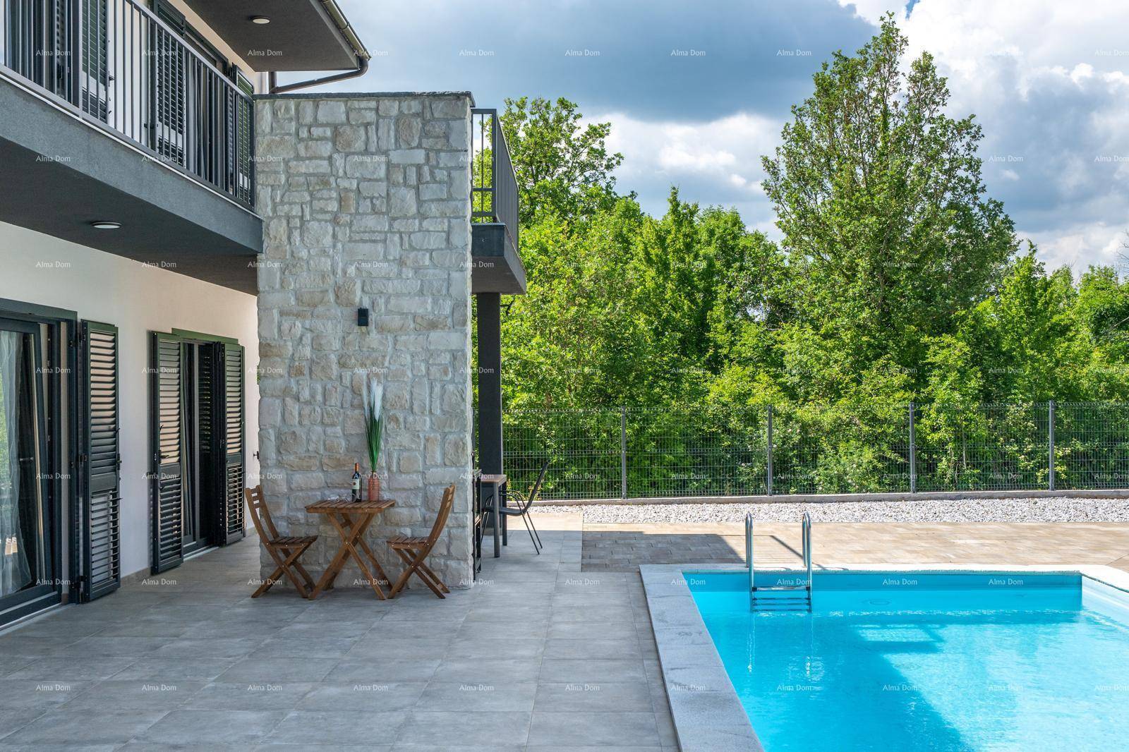 Seitliche Terrasse mit kleinem Holztisch und Stühlen, angrenzend an den Poolbereich.