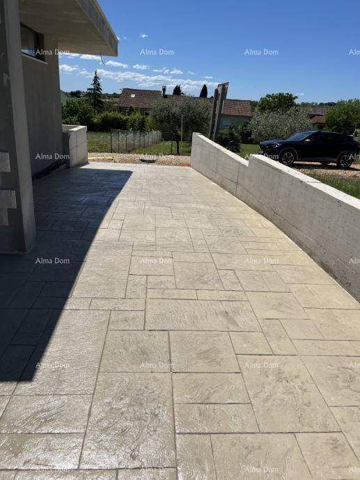 Gepflasterte Zufahrt zum Haus mit einer stabilen Betonmauer.