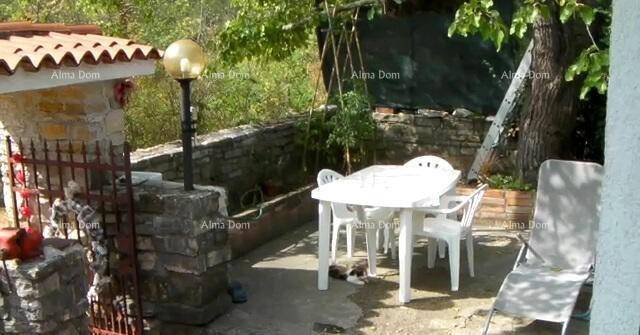 Gemütliche Terrasse mit Gartenmöbeln und Laterne, umgeben von Steinmauern und Bäumen.