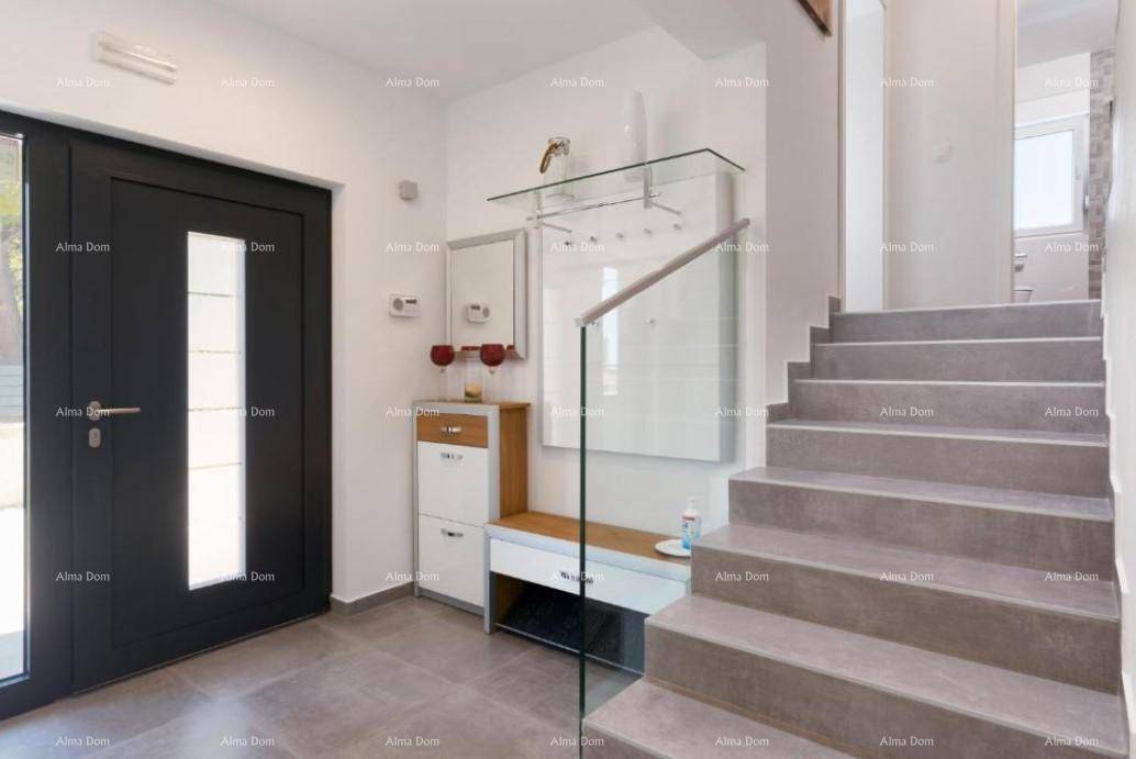 Heller Eingangsbereich mit moderner Treppe, Glasgeländer und kleiner Garderobe.