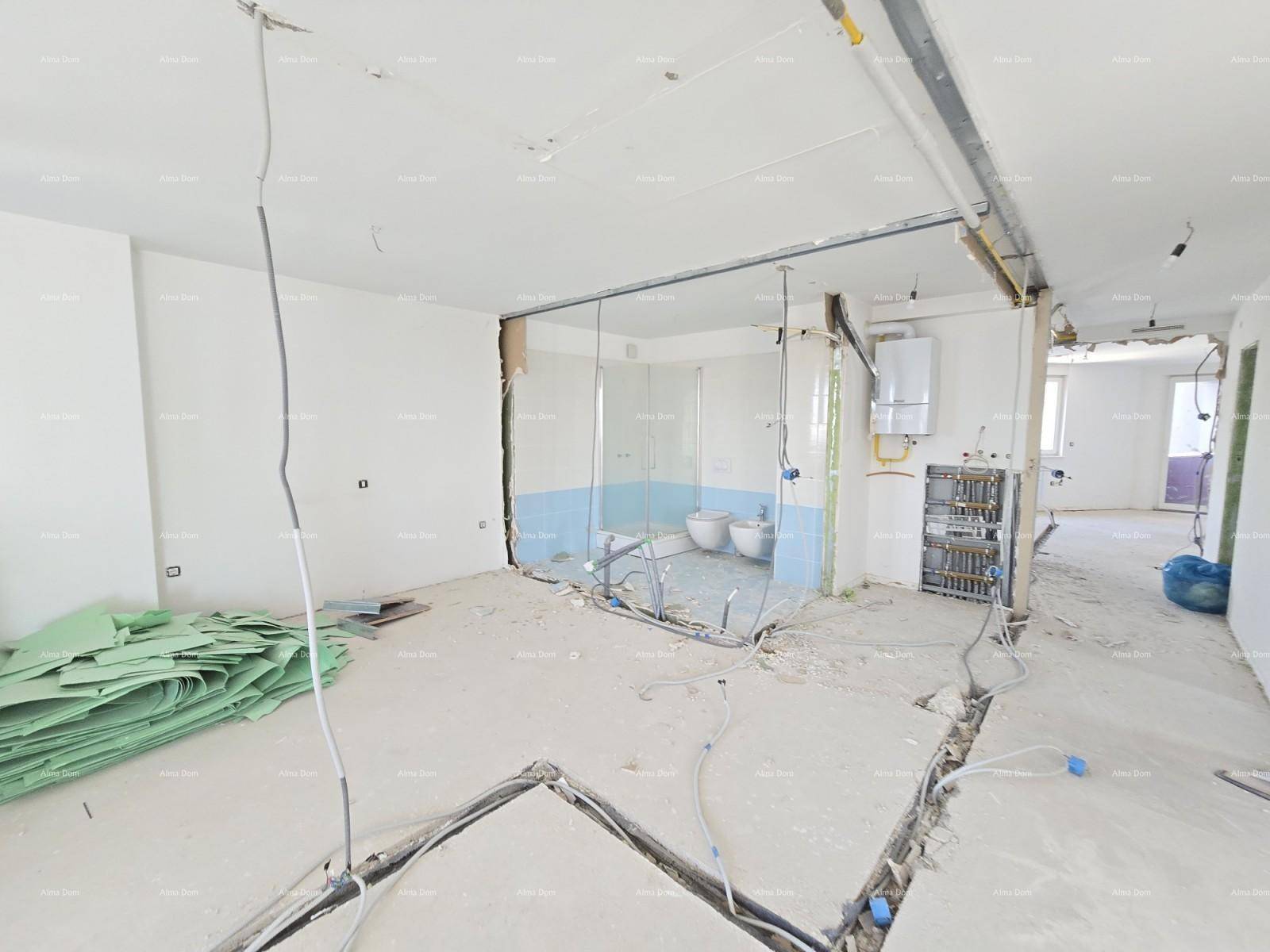 Innenraum im Rohbau mit sichtbaren Leitungen und einem teilweise erkennbaren Badezimmerbereich.