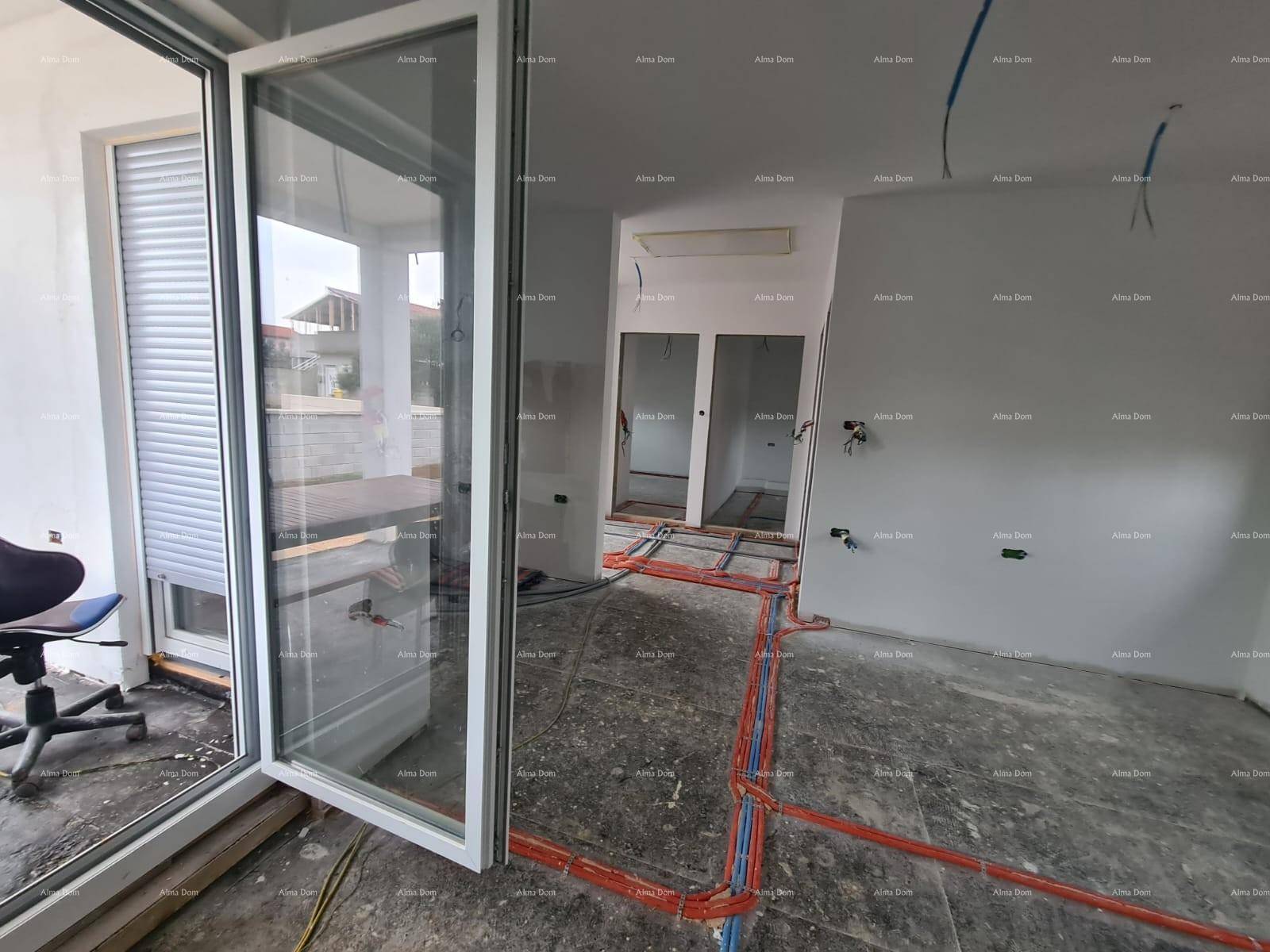 Innenraum im Rohbau mit sichtbaren Leitungen für Fußbodenheizung und großer Glasschiebetür zur Terrasse.