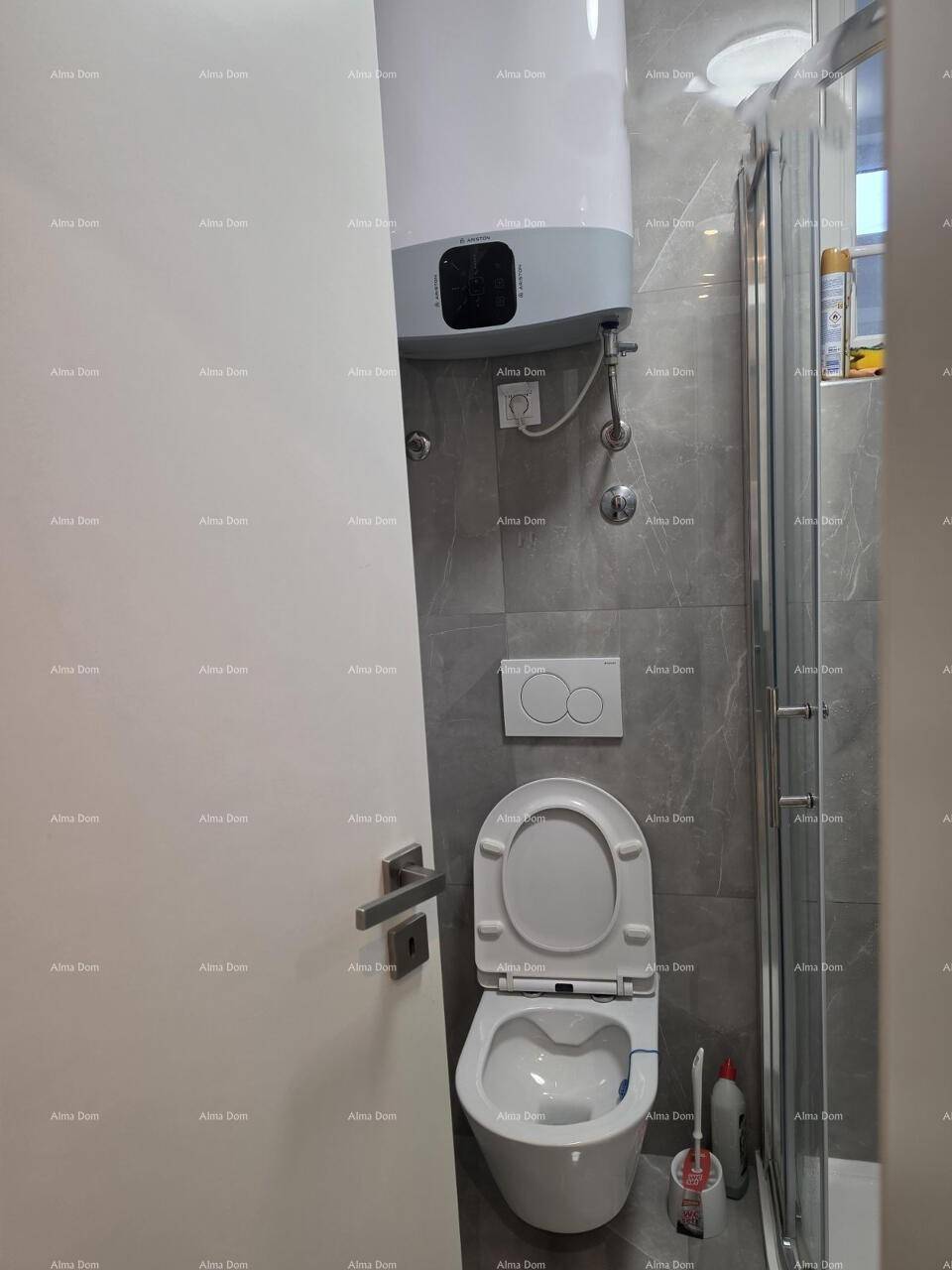 Badezimmer mit Wand-WC, Warmwasserboiler und modernen grauen Fliesen.