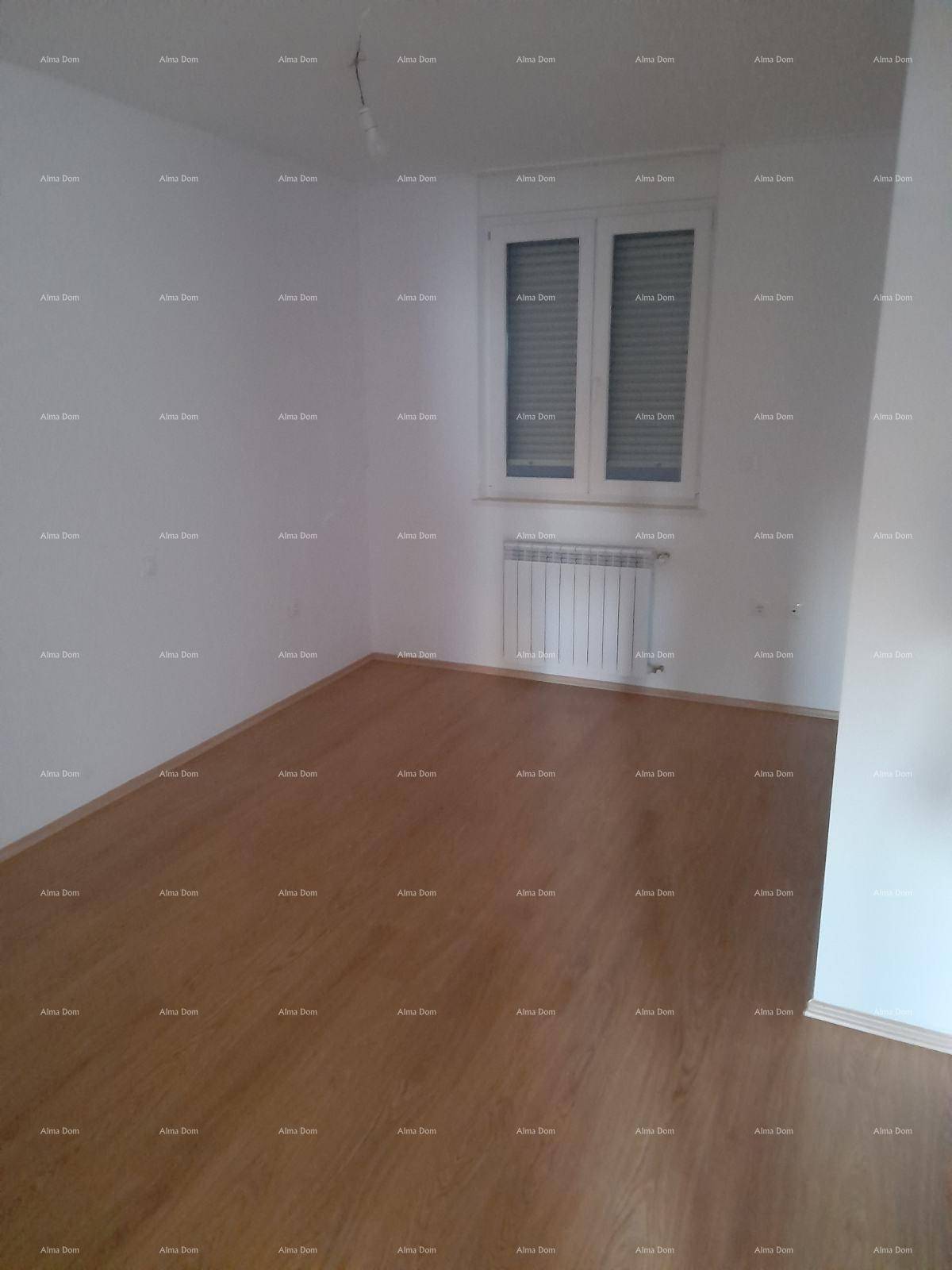 Leeres Schlafzimmer mit Holzboden, weißen Wänden und Fenster mit Rollläden.