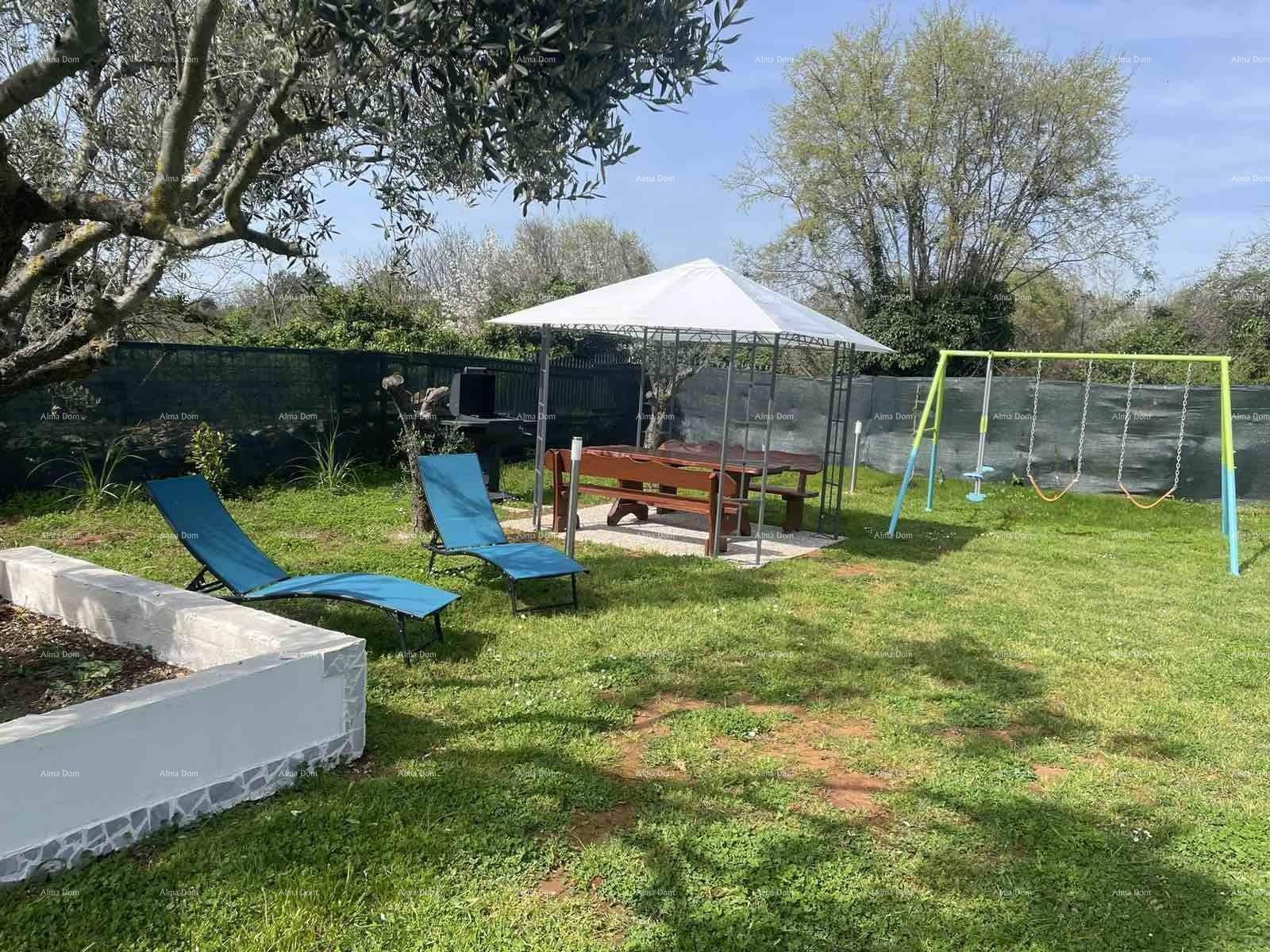 Weitläufiger Garten mit Rasen, einem Pavillon, Liegestühlen und einem Spielbereich unter blauem Himmel.